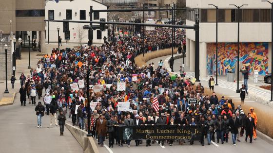 Large crowd of people walking through the streets of downtown Lexington during the MLK Day march