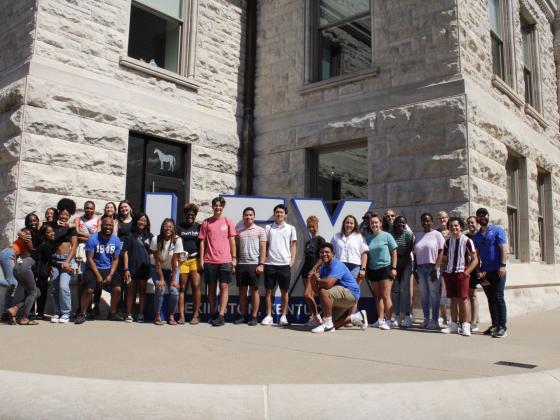group of students standing outside in front of large letters spelling LEX