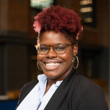 headshot of woman inside wearing black blazer and glasses