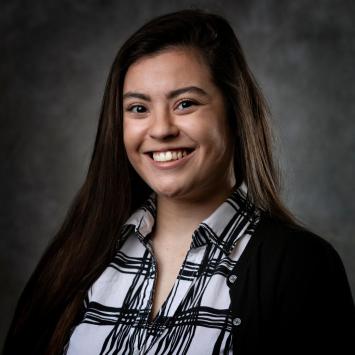 headshot of woman in black and white plaid shirt with black sweater