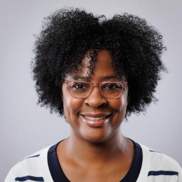 headshot of woman wearing glasses and a white sweater with black stripes