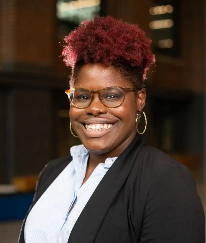 headshot of woman inside wearing black blazer and glasses