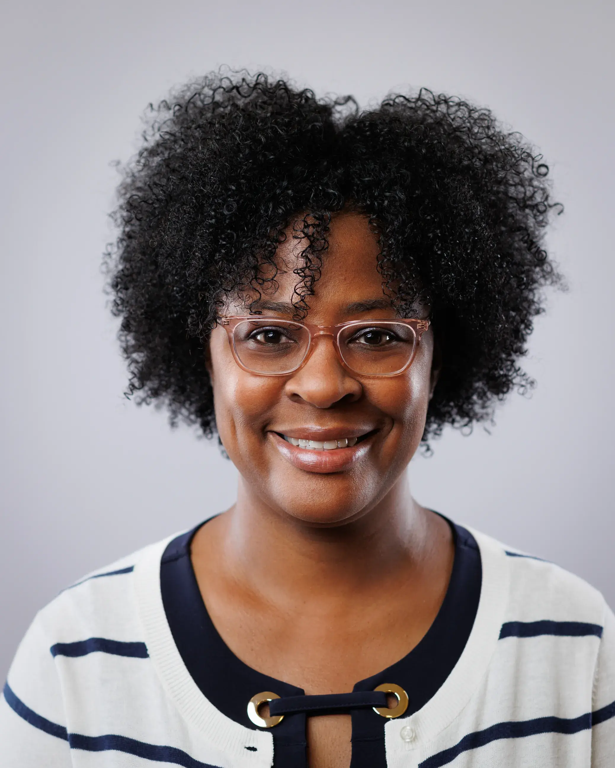 headshot of woman wearing glasses and a white sweater with black stripes